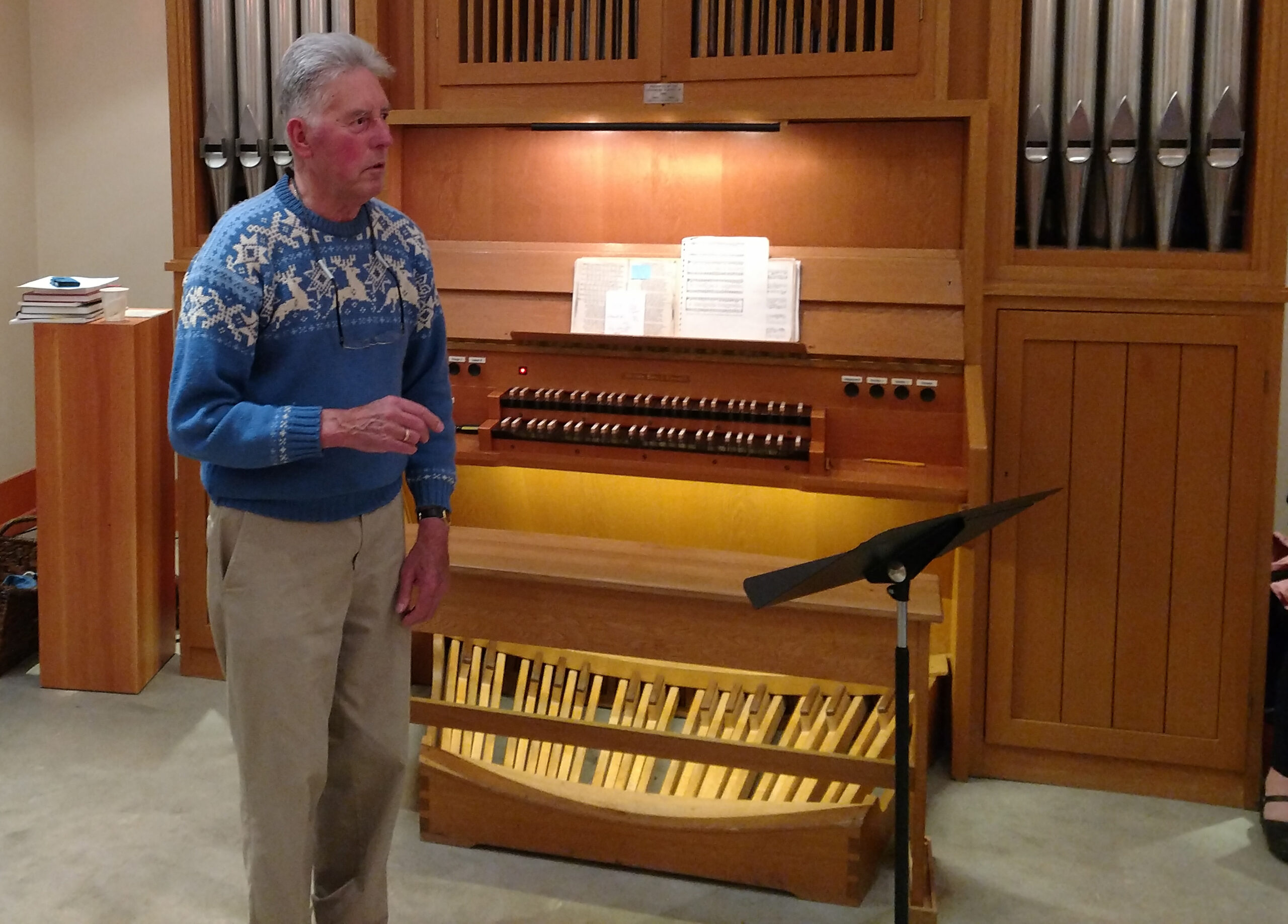 Man wearing sweater stands in front of pipe organ