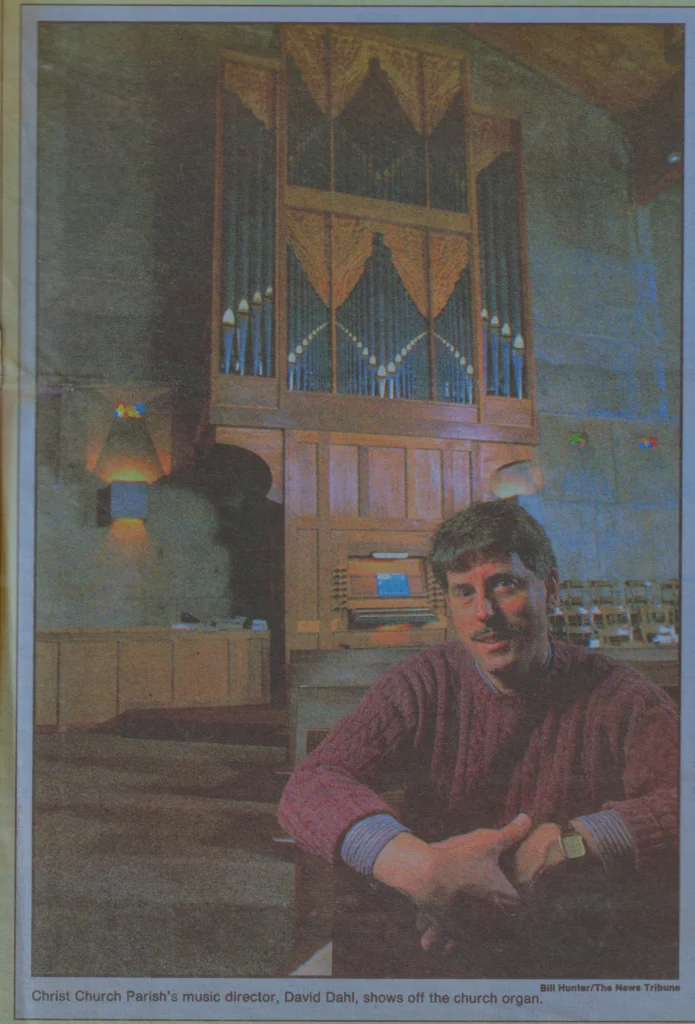 Newspaper clipping showing man sitting in front of pipe organ